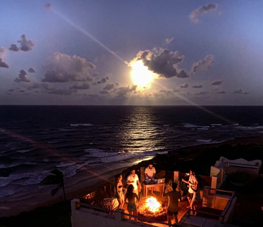 Festa ao redor da fogueira com DJ e vista para o oceano ao entardecer no Kilombo Villas