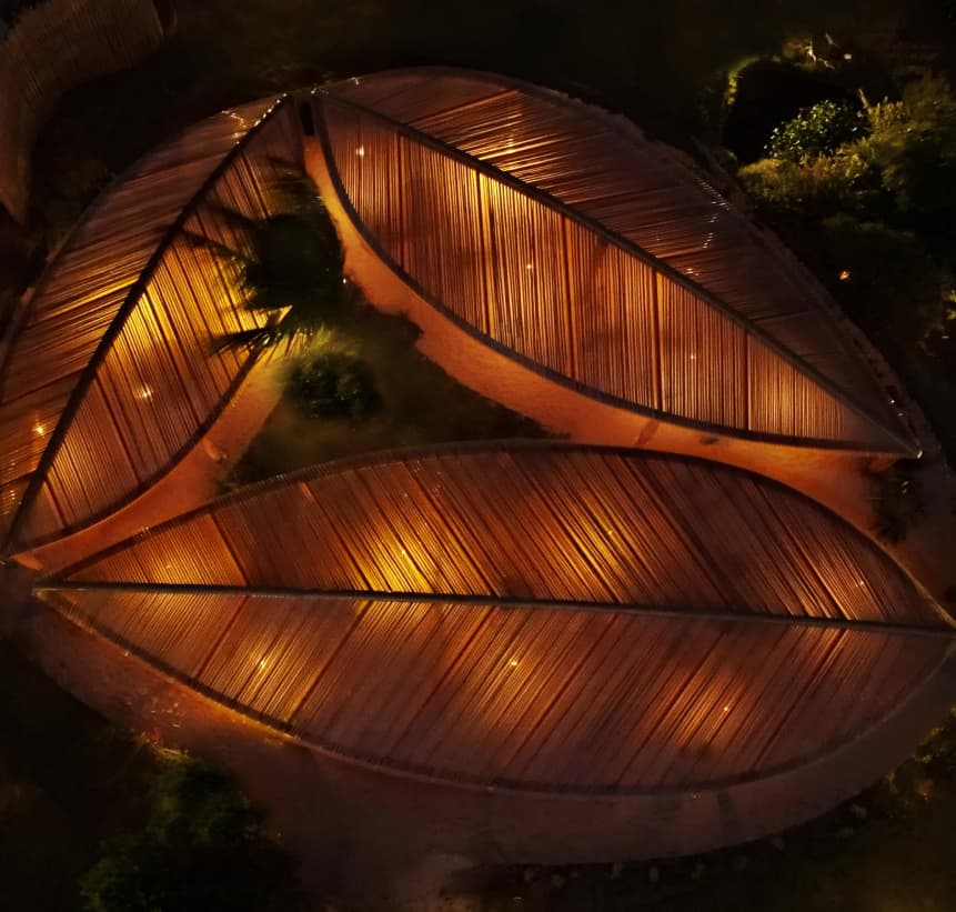 Vista aérea noturna do telhado em forma de folha iluminado do Kibo Restaurante no Kilombo Villas