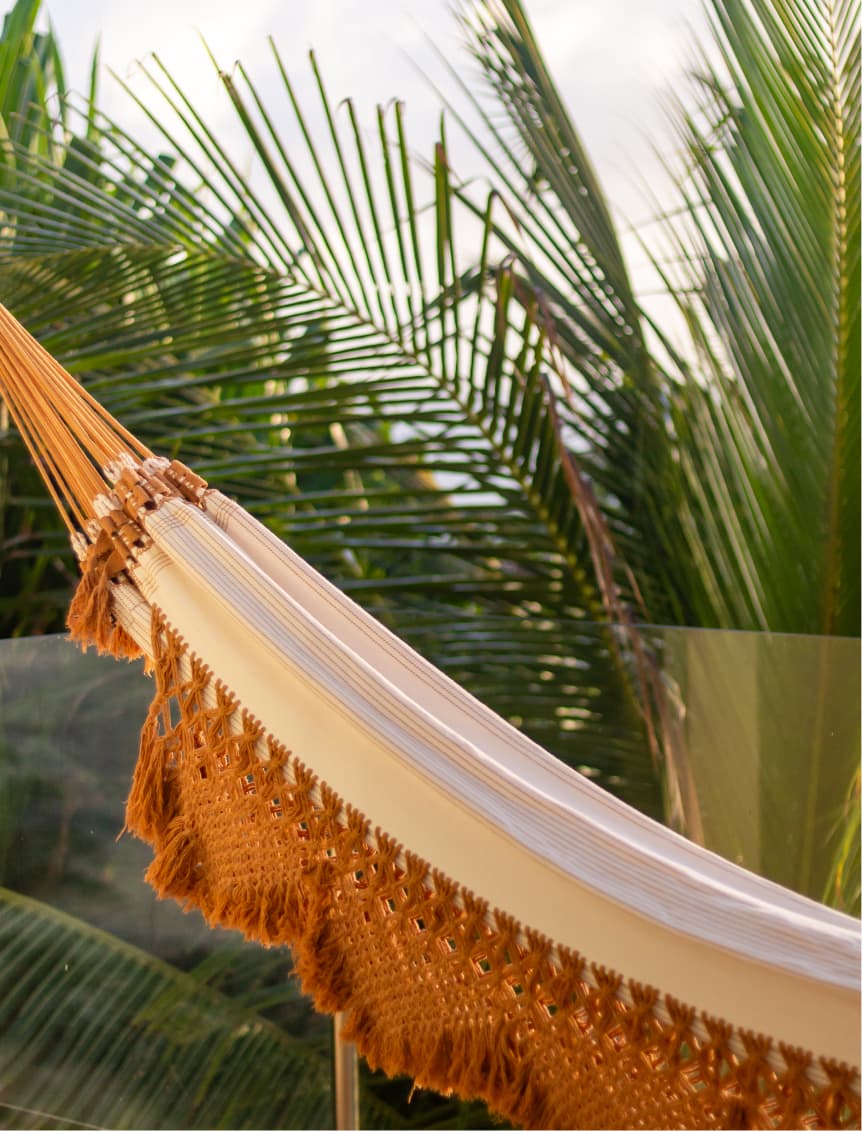 Rede artesanal com franjas entre palmeiras tropicais no Kilombo Villas