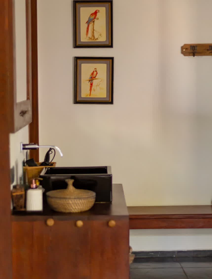 Kilombo Villas - villa Jacú Jardim - Casa de estilo tropical rodeada por árvores de coco e plantas exuberantes, com varanda e janelas de madeira, situada em um ambiente natural e ensolarado.