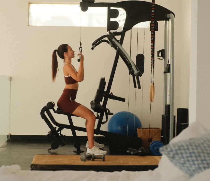 Kilombo Villas - villa Jacú Ocean - Hóspede utilizando a área de academia privativa da villa Jacú Ocean. O espaço é equipado com máquinas de musculação modernas, acessórios de treino e possui iluminação natural abundante.