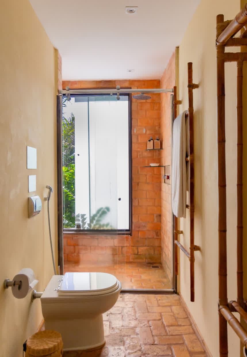 Kilombo Villas - villa Sibraáma Jardim - Cozinha rústica ao ar livre com fogão à lenha, bancada de madeira rústica, utensílios pendurados e decoração natural, integrada ao ambiente tropical.