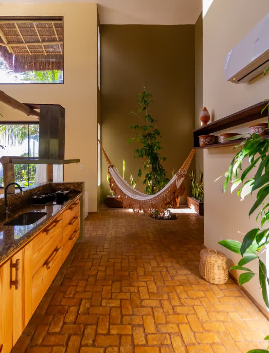 Kilombo Villas - villa Sibraáma Jardim - Sala de estar moderna com ar-condicionado split, sofá confortável e decoração rústica, com janela ampla que permite a entrada de luz natural e vista para a vegetação externa.