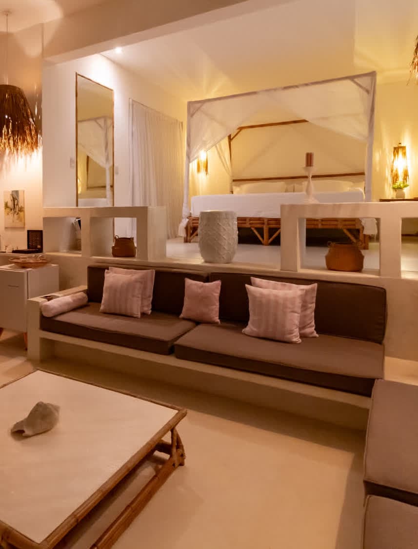 Kilombo Villas - Das Rosas - Imagem de um quarto de hotel com decoração moderna e elegante, destaque para a cama com dossel, iluminação suave, almofadas e móveis de design minimalista.