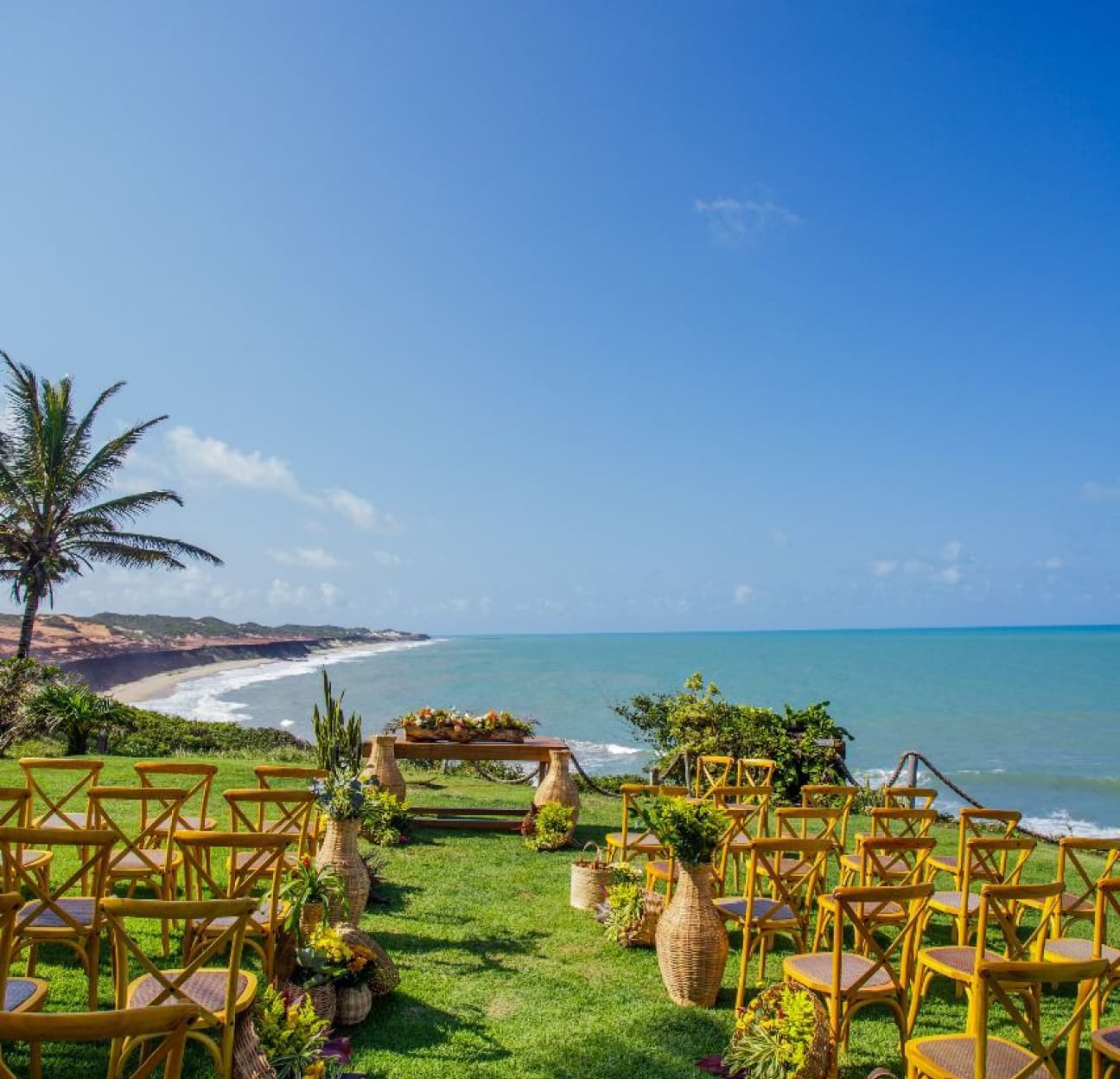 Arranjo da cerimônia com cadeiras amarelas e flores tropicais com vista para o mar de Sibaúma no Kilombo Villas