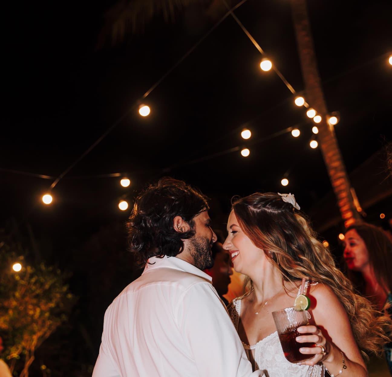 Casal dançando abraçado sob cordas de luzes na recepção noturna de casamento no Kilombo Villas