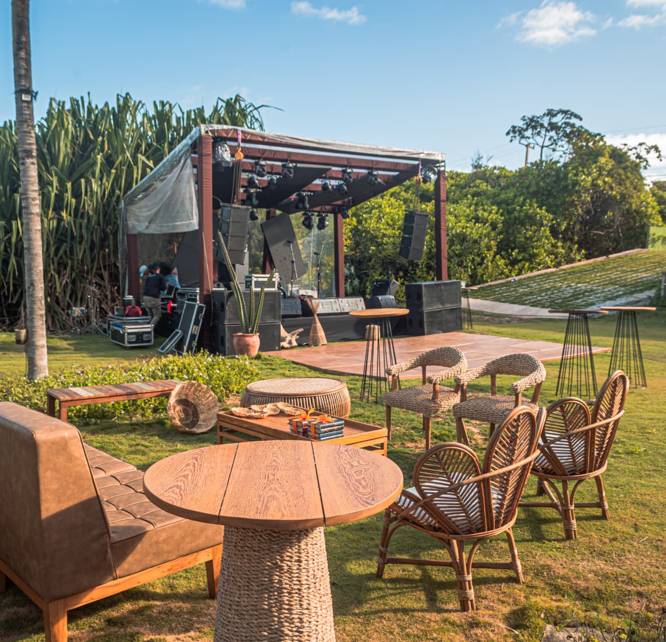 Palco e espaço de recepção ao ar livre com mobília de ratan no jardim do Kilombo Villas