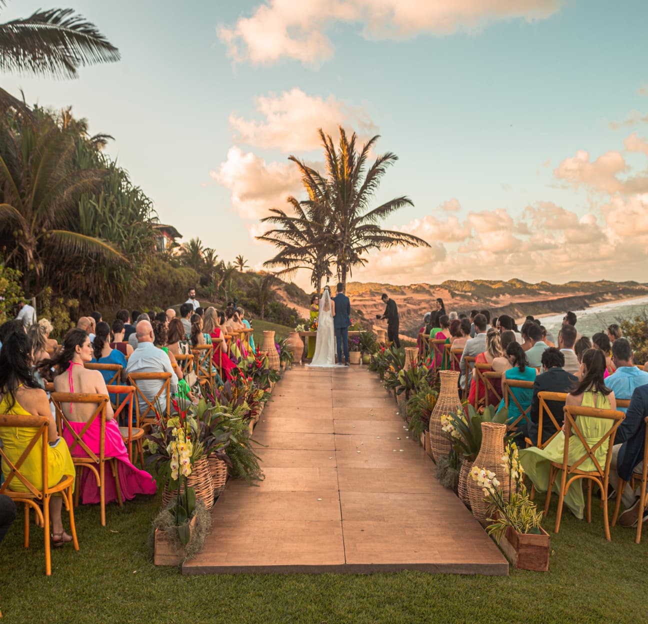 Cerimônia de casamento ao pôr do sol com convidados sentados ao longo do corredor externo no Kilombo Villas