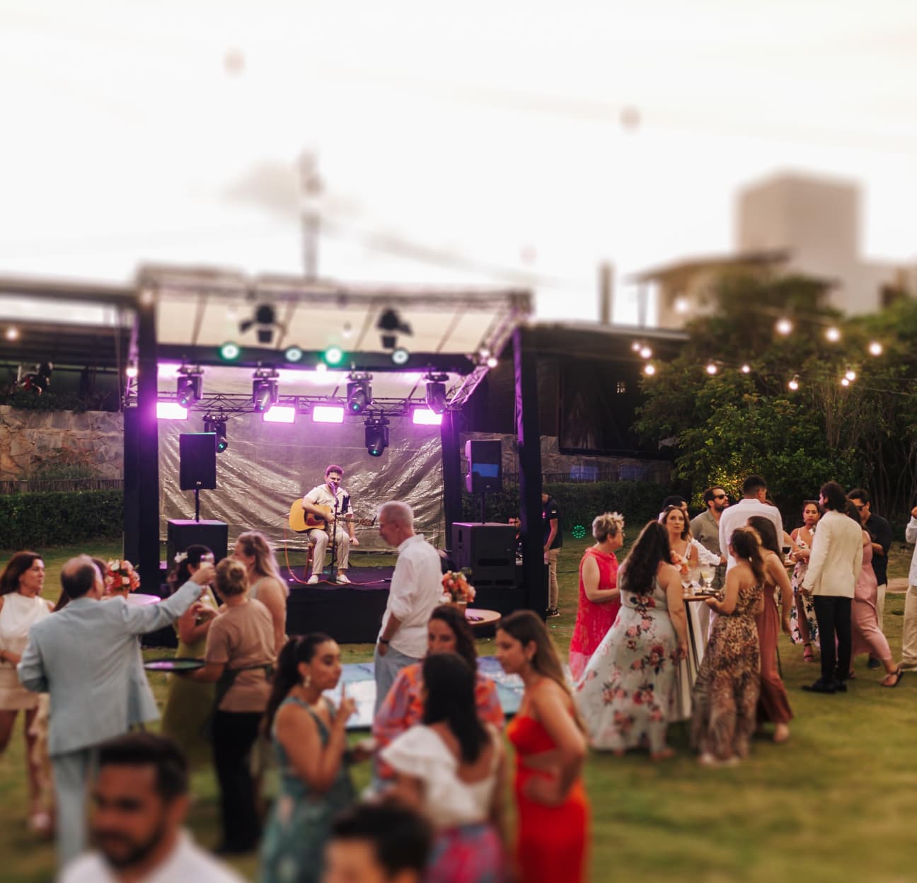Show ao vivo com músico no palco e convidados dançando na recepção de casamento ao ar livre no Kilombo Villas