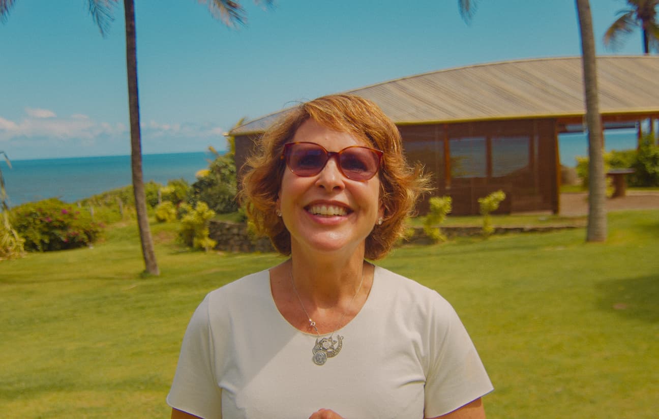 Hóspede sorridente nos jardins do Kilombo Villas com vista para o mar de Sibaúma