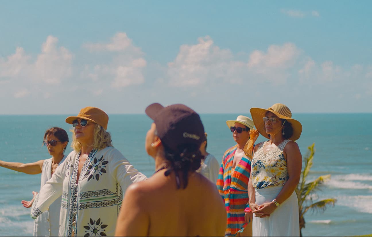 Grupo de hóspedes reunido à beira-mar durante prática guiada na praia de Sibaúma