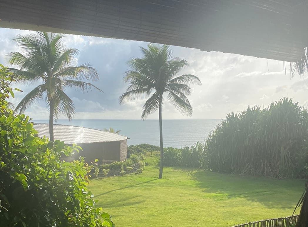 Vista de coqueiros e o mar de Sibaúma a partir de varanda coberta de palha no Kilombo Villas