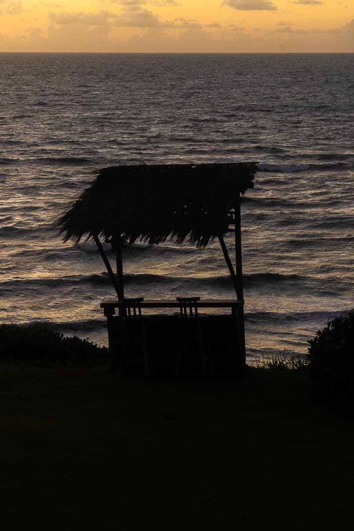 Silhueta de quiosque rústico de palha ao pôr do sol com vista para o oceano em Sibaúma
