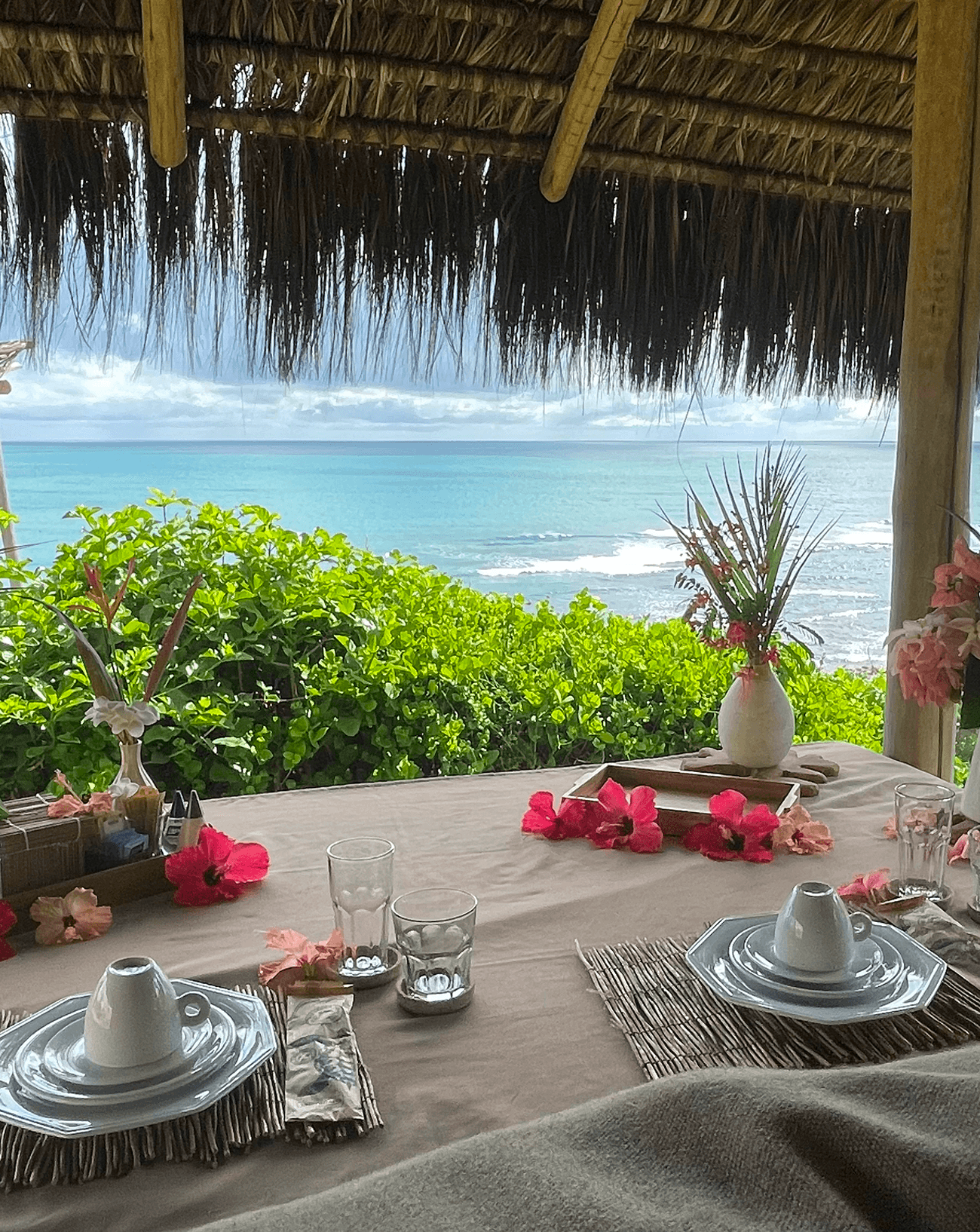 Mesa de café da manhã decorada com flores de hibisco com vista para o oceano de Sibaúma no Kilombo Villas