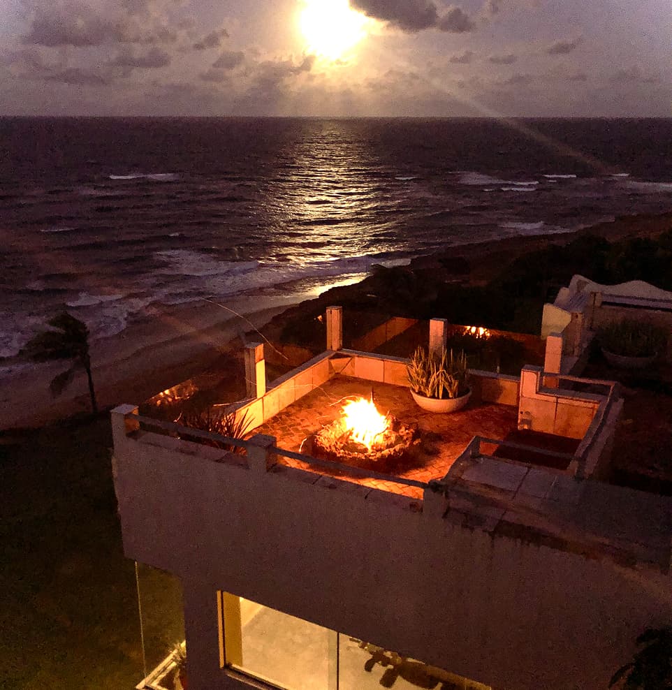 Fogueira acesa no terraço de uma villa com vista para o mar sob a luz da lua no Kilombo Villas