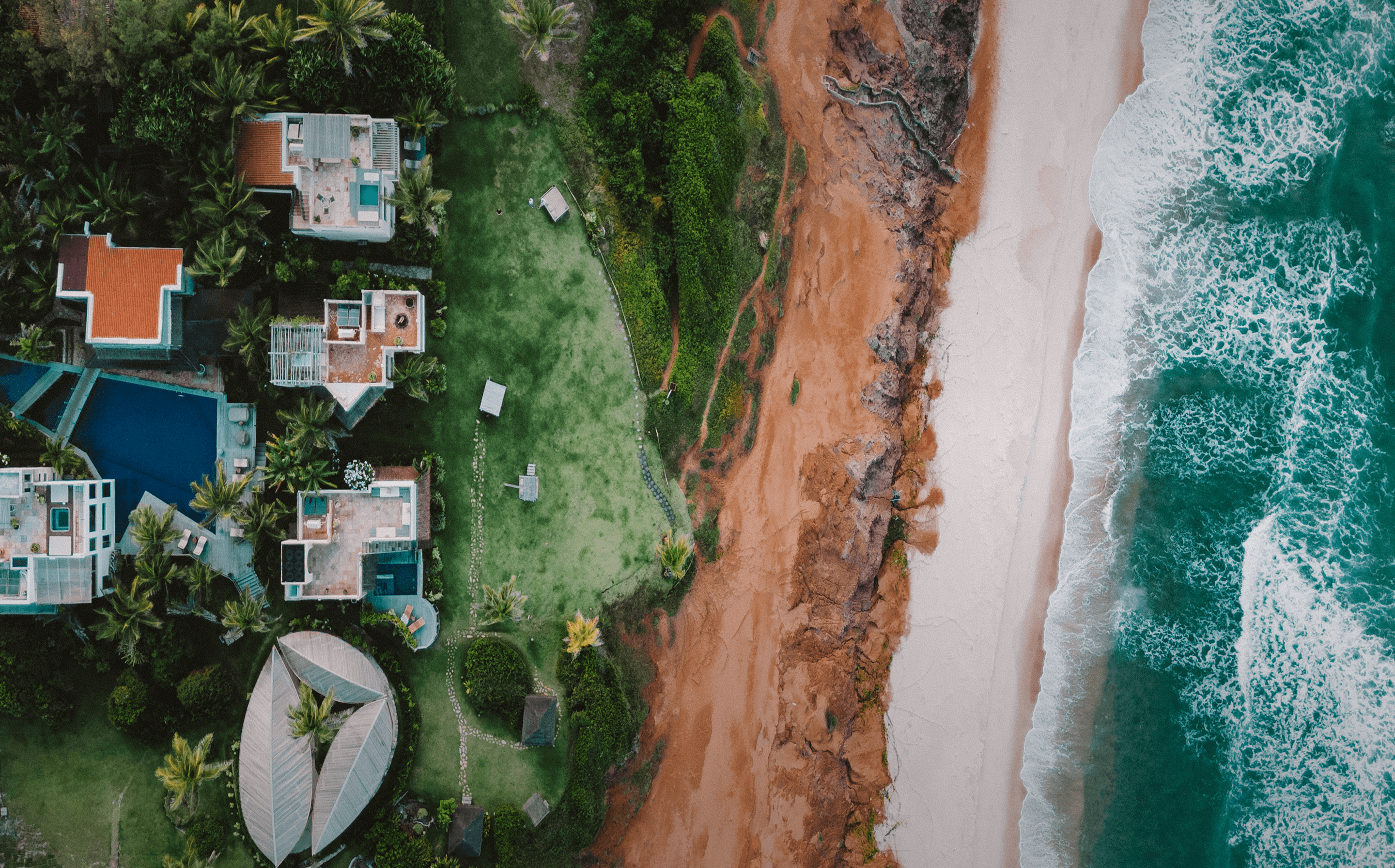 Vista aérea do Kilombo Villas com villas, piscinas e jardins às margens das falésias e da praia de Sibaúma