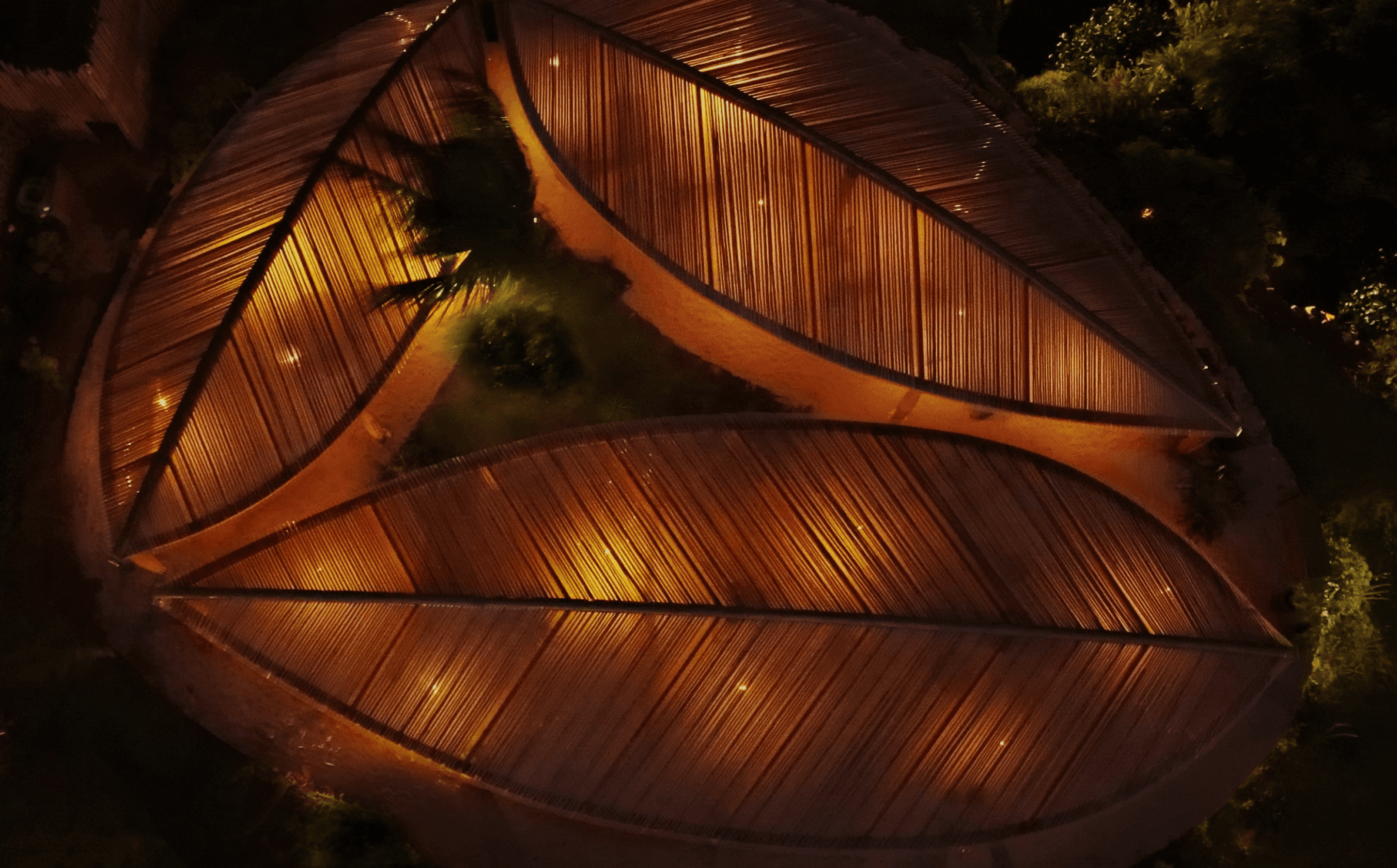 Vista aérea noturna do telhado em forma de folha iluminado do Kibo Restaurante no Kilombo Villas