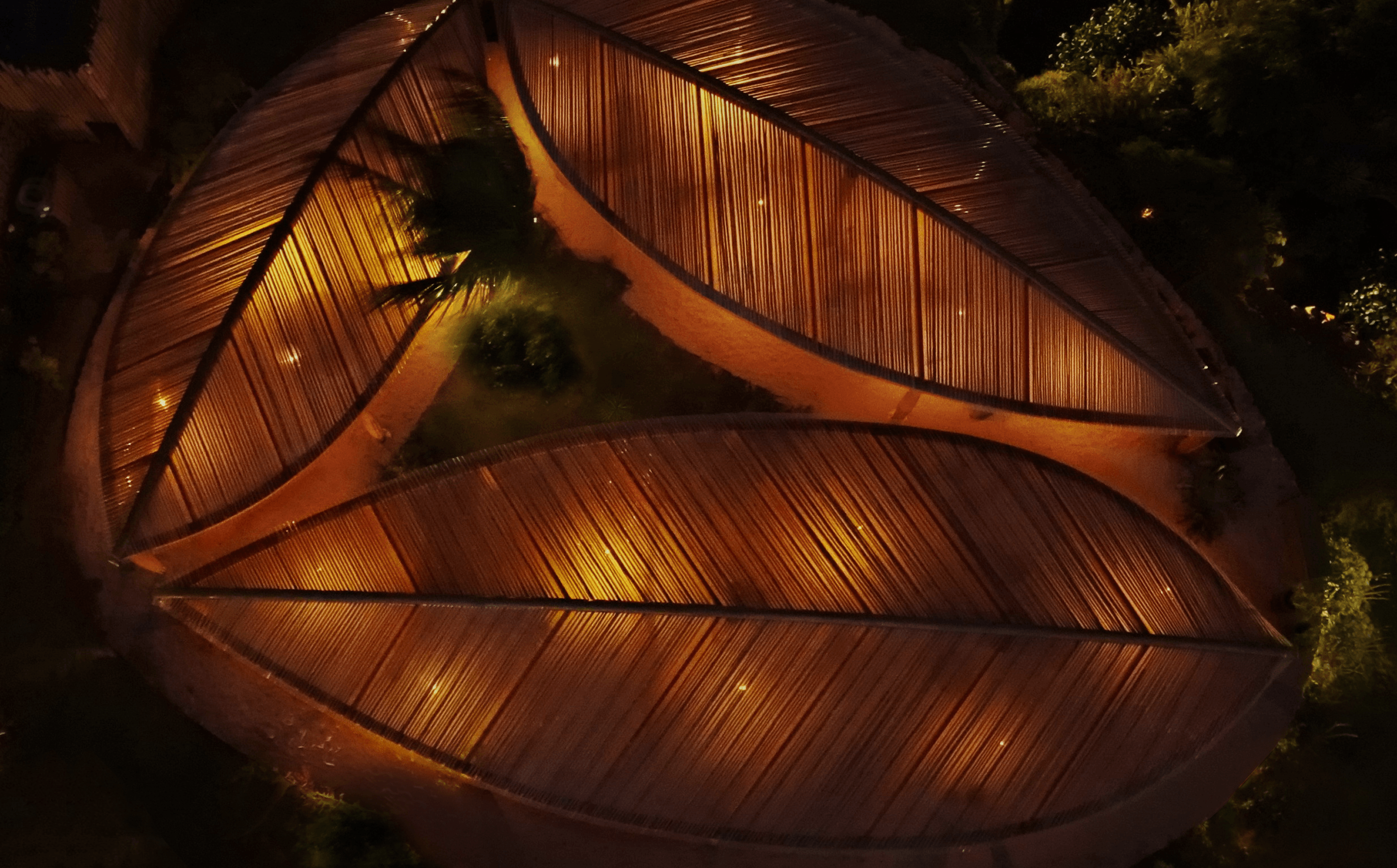 Vista aérea noturna do telhado em forma de folha iluminado do Kibo Restaurante no Kilombo Villas