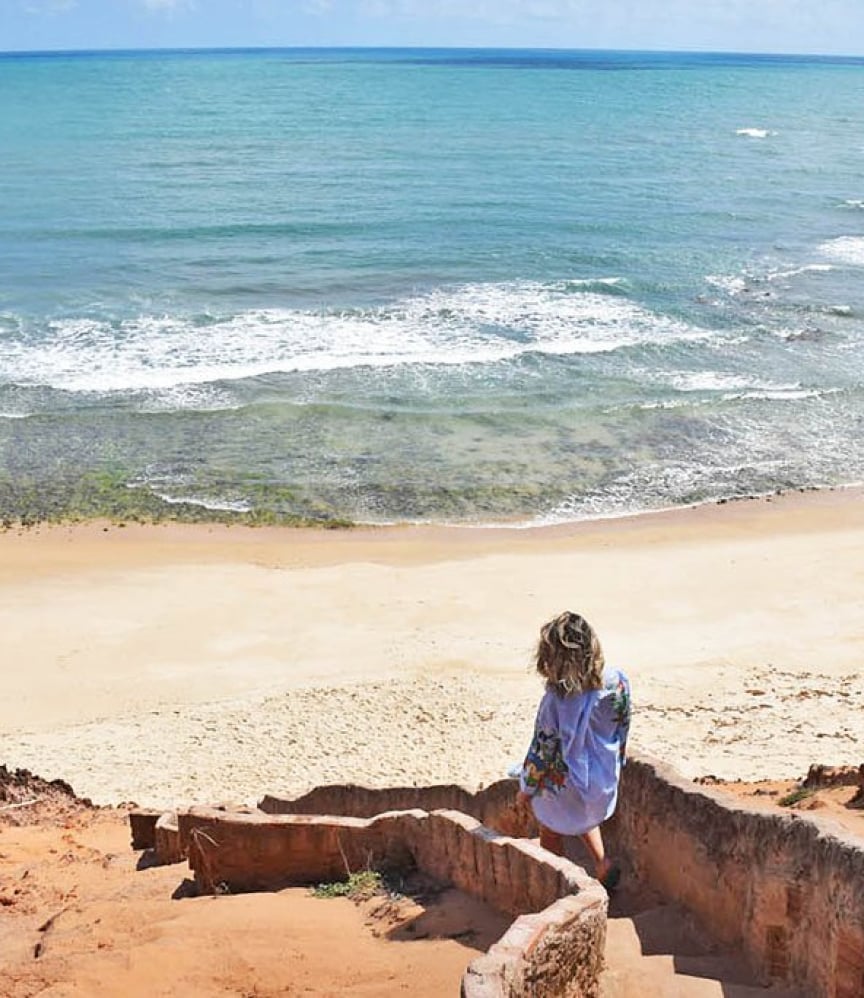 Guest descending stone steps towards Sibaúma beach at Kilombo Villas