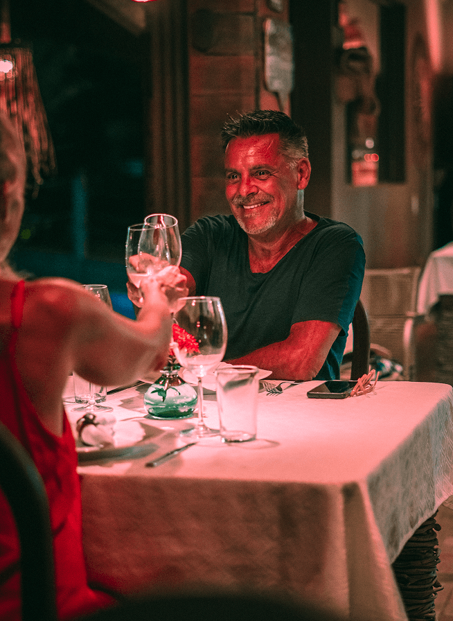 Casal brindando com taças de vinho em jantar romântico no Kibo Restaurante, Kilombo Villas
