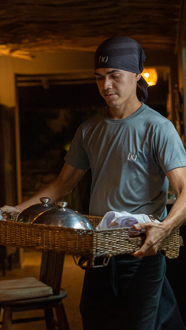 Funcionário do Kibo Restaurante transportando bandeja de serviço com cloche no Kilombo Villas