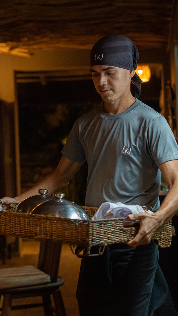 Funcionário do Kibo Restaurante transportando bandeja de serviço com cloche no Kilombo Villas