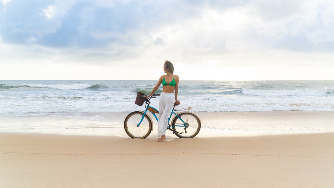 Mulher com bicicleta na praia de Sibaúma ao amanhecer
