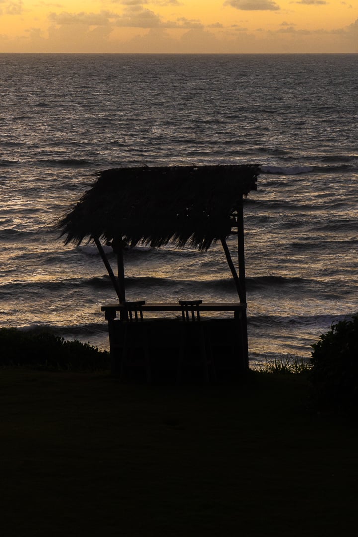Silhueta de quiosque rústico de palha ao pôr do sol com vista para o oceano em Sibaúma