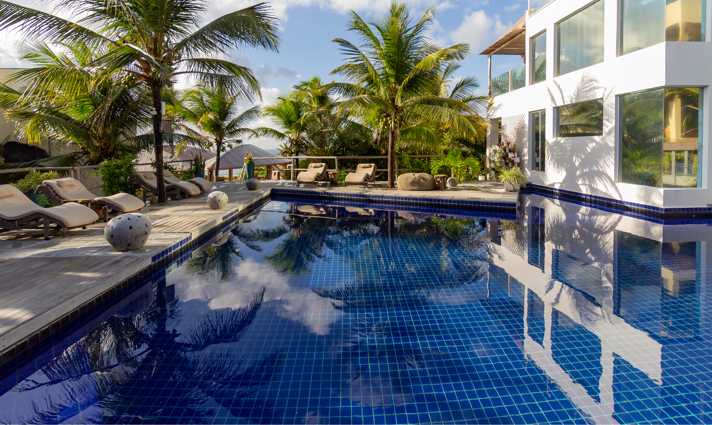 Piscina do Kilombo Villas com espreguiçadeiras, deck de madeira e palmeiras tropicais