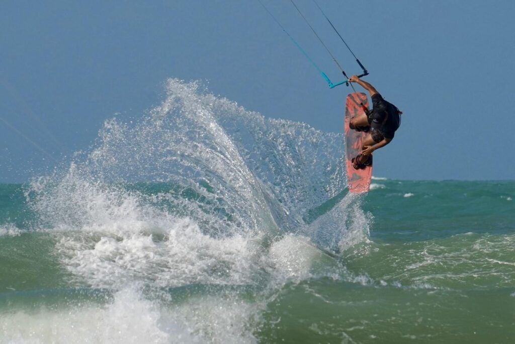 Praticantes de kitesurf nas águas turquesa da Praia de Pipa em dia de vento