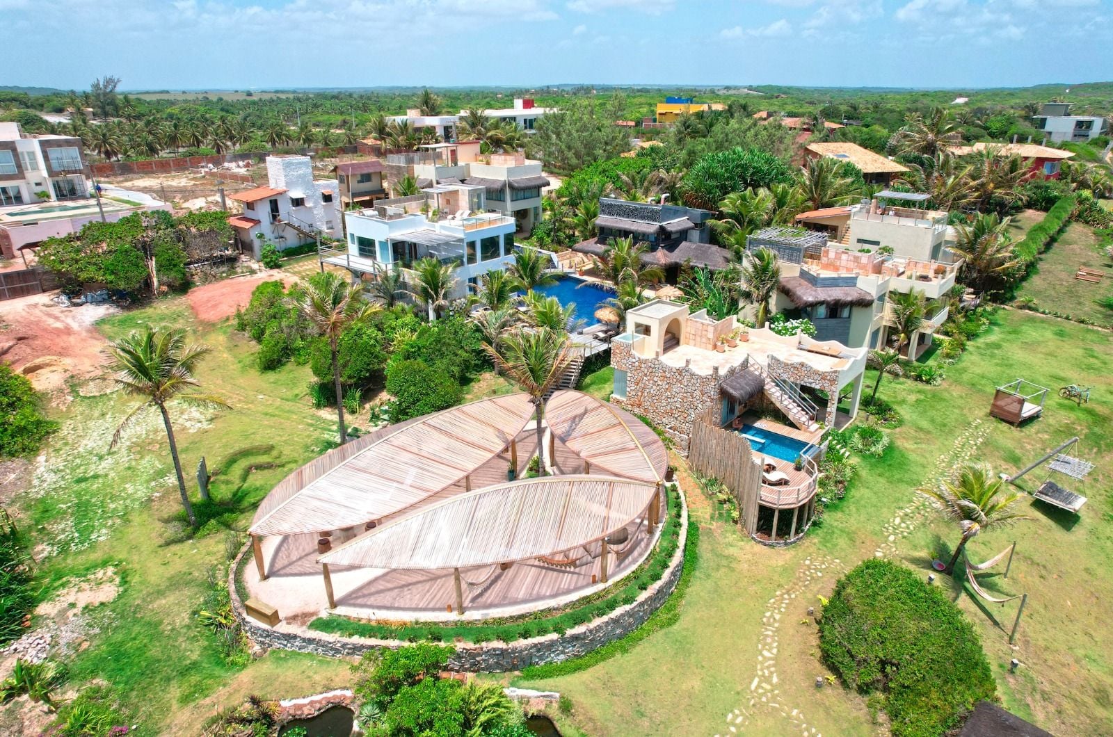 Vista aérea do condomínio Kilombo Villas com estrutura oval em madeira e piscinas
