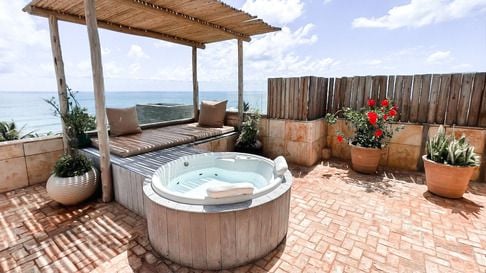 Jacuzzi na cobertura com vasos de flores e vista panorâmica para o oceano