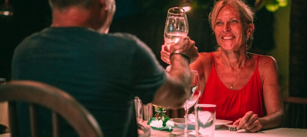 Casal brindando com taças de vinho em jantar romântico noturno no restaurante
