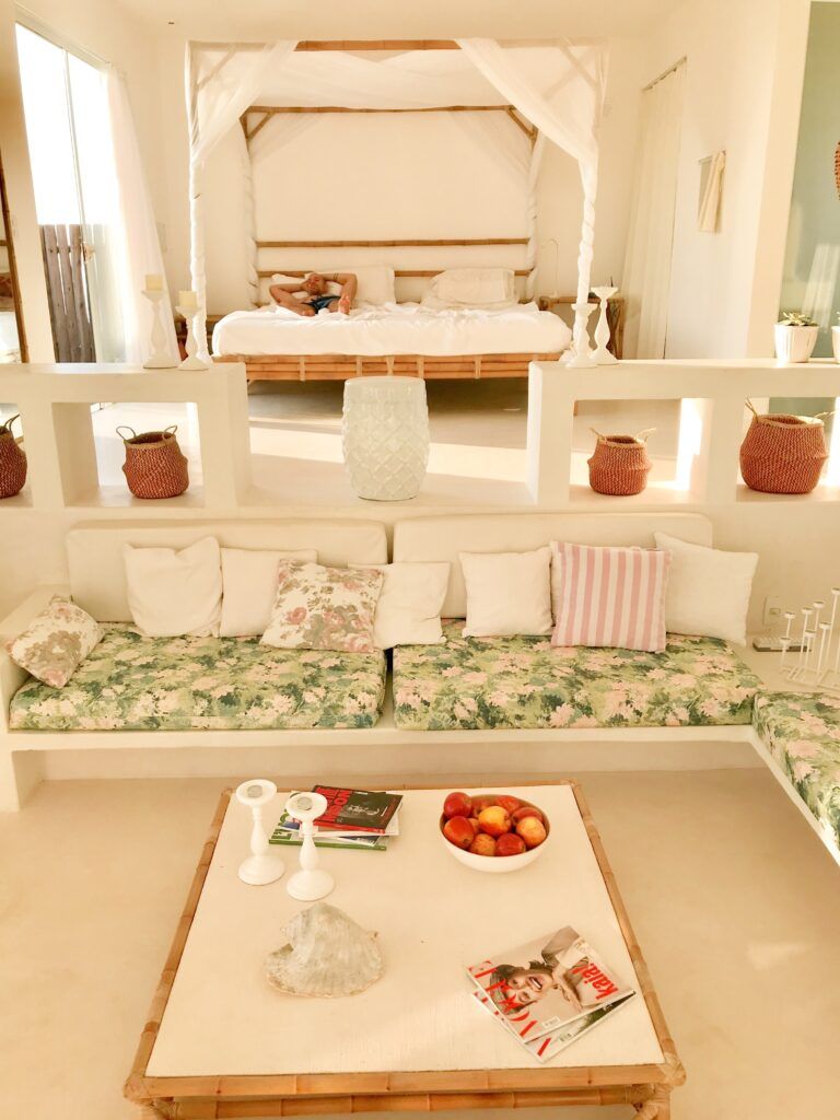 Sala de estar de villa com sofá, mesa de madeira e objetos decorativos com jardim ao fundo