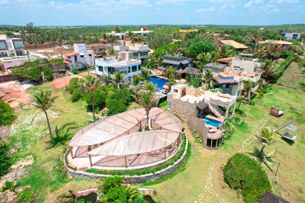 Vista aérea do condomínio Kilombo Villas com estrutura oval de madeira e jardins verdes