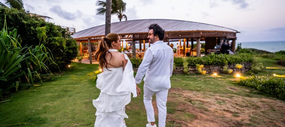 Casal de mãos dadas caminhando em direção à estrutura folha iluminada do Kilombo Villas