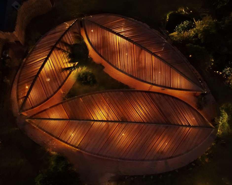 Vista aérea noturna da estrutura em forma de folha do Kilombo Villas iluminada dourada