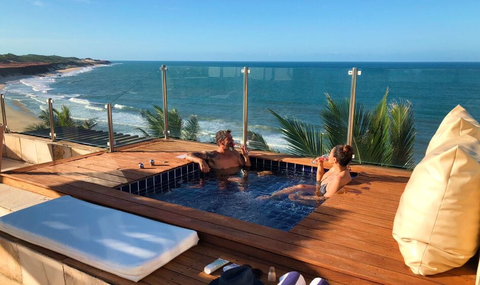 Casal em jacuzzi no deck de madeira com vista para o litoral de Sibauma e falésias