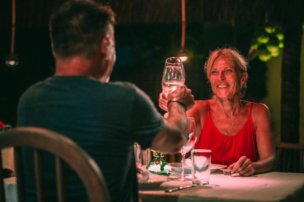 Casal brindando com taças de vinho em jantar romântico noturno no Kibo Restaurante