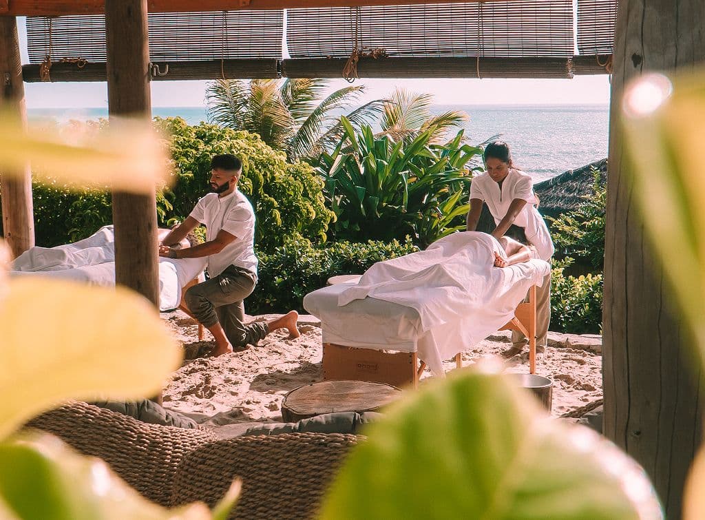 Massagem para casal ao ar livre, em meio à vegetação e com vista para o mar, no Kilombo Villas
