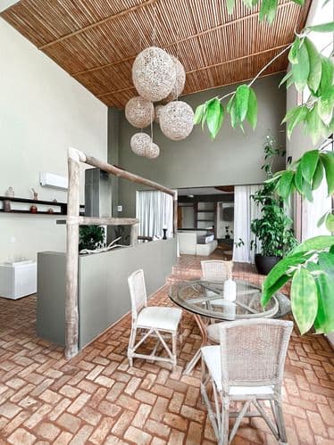 Sala de jantar moderna com mesa redonda de vidro e luminárias de macramê