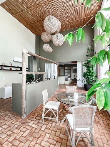 Sala de jantar moderna com mesa redonda de vidro e luminárias de macramê